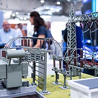 Ein technisches Gerät, im hintergrund unterhalten sich 3 Personen auf der netze:ON 2023